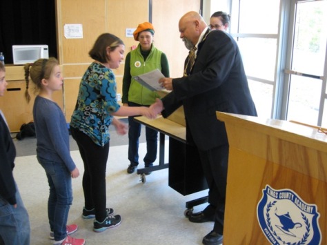 Mayor Corkum hands out copies of "Pumpkin People" to Grade 3 students while Sandra looks on.